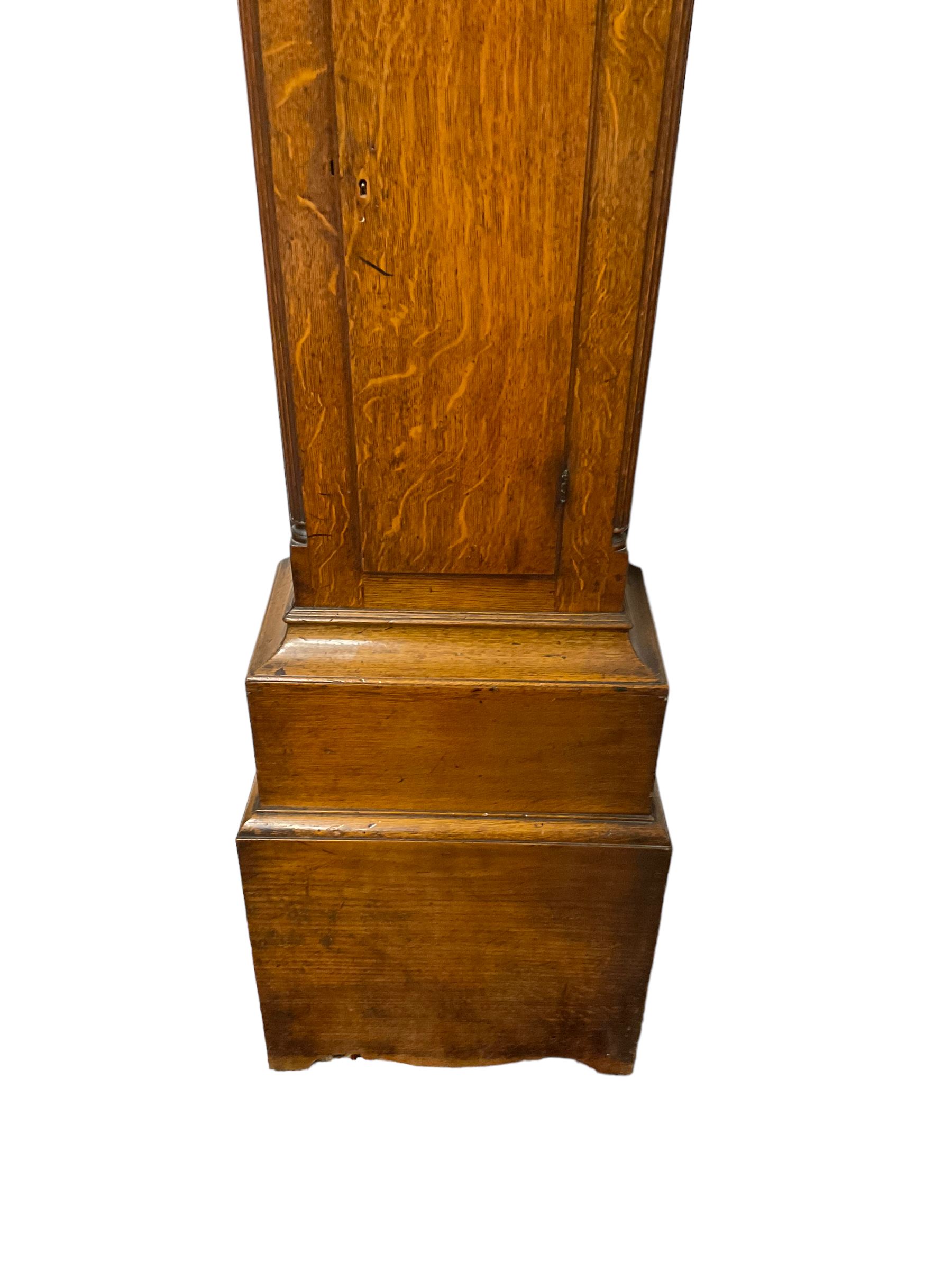 George Clapham of Brigg - Late 18th century 8-day oak cased longcase clock c1790 - flat topped hood with later carved addition, dog tooth moulding and blind fretwork beneath, break arch hood door flanked by reeded pilasters and capitals, trunk with canted corners and  door with a triple arched top, plinth with a later base with decoratively shaped feet, early painted dial with flowers enclosed in a gesso border to the spandrels, rolling moon to the arch, seconds dial and calendar aperture, Roman numerals and five minute Arabic's with makers name (indistinct), dial pinned via a false plate to a rack striking movement. With weights, key and pendulum.