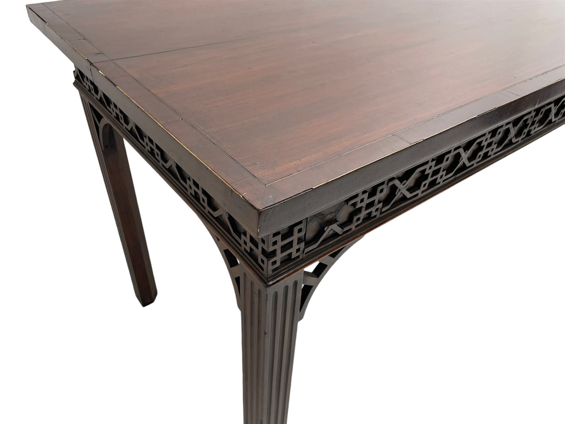 In the manner of Thomas Chippendale - early 19th century mahogany serving table, rectangular crossbanded top with boxwood stringing, the frieze with upper moulding over applied geometric fretwork, the left-hand side fitted with slide, on fluted square supports with inner chamfer 
