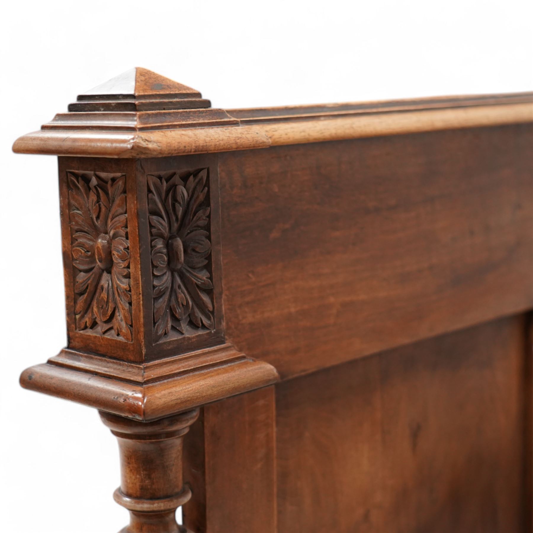Late 19th century French walnut double bedstead, the panelled headboard with curling foliage carved frieze over concentric turned roundels and faceted mounts, lion mask carved rails with applied panelled mounts, matching footboard with lower carved lion mask 