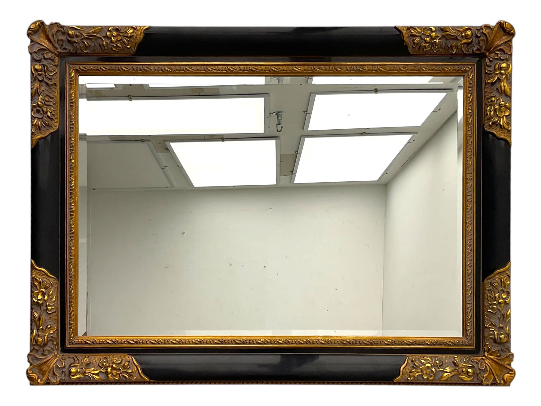 Early 20th century wall-hanging mirror, rectangular bevelled mirror plate within ebonised frame, gilt mounts to the corners carved with floral motifs 