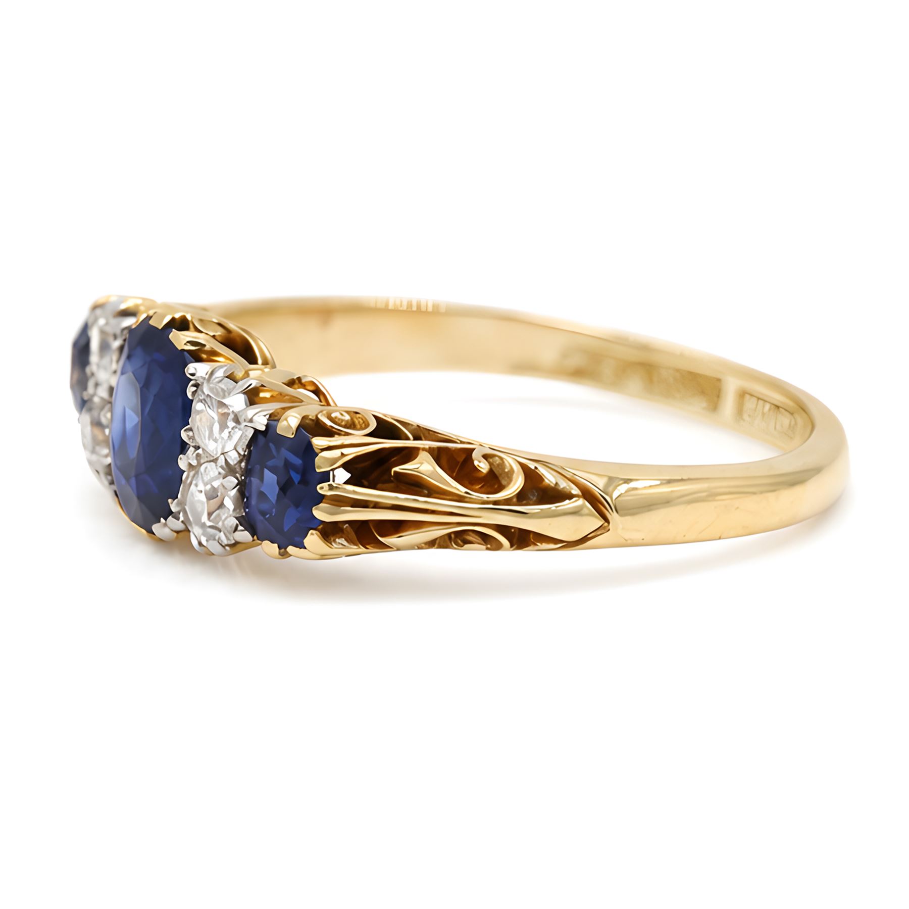 Early 20th century gold sapphire and diamond ring, three vari-cut sapphires, spaced by four old cut diamonds, with scroll design shoulders, stamped 18ct, total sapphire weight approx 1.45 carat, total diamond weight approx 0.30 carat