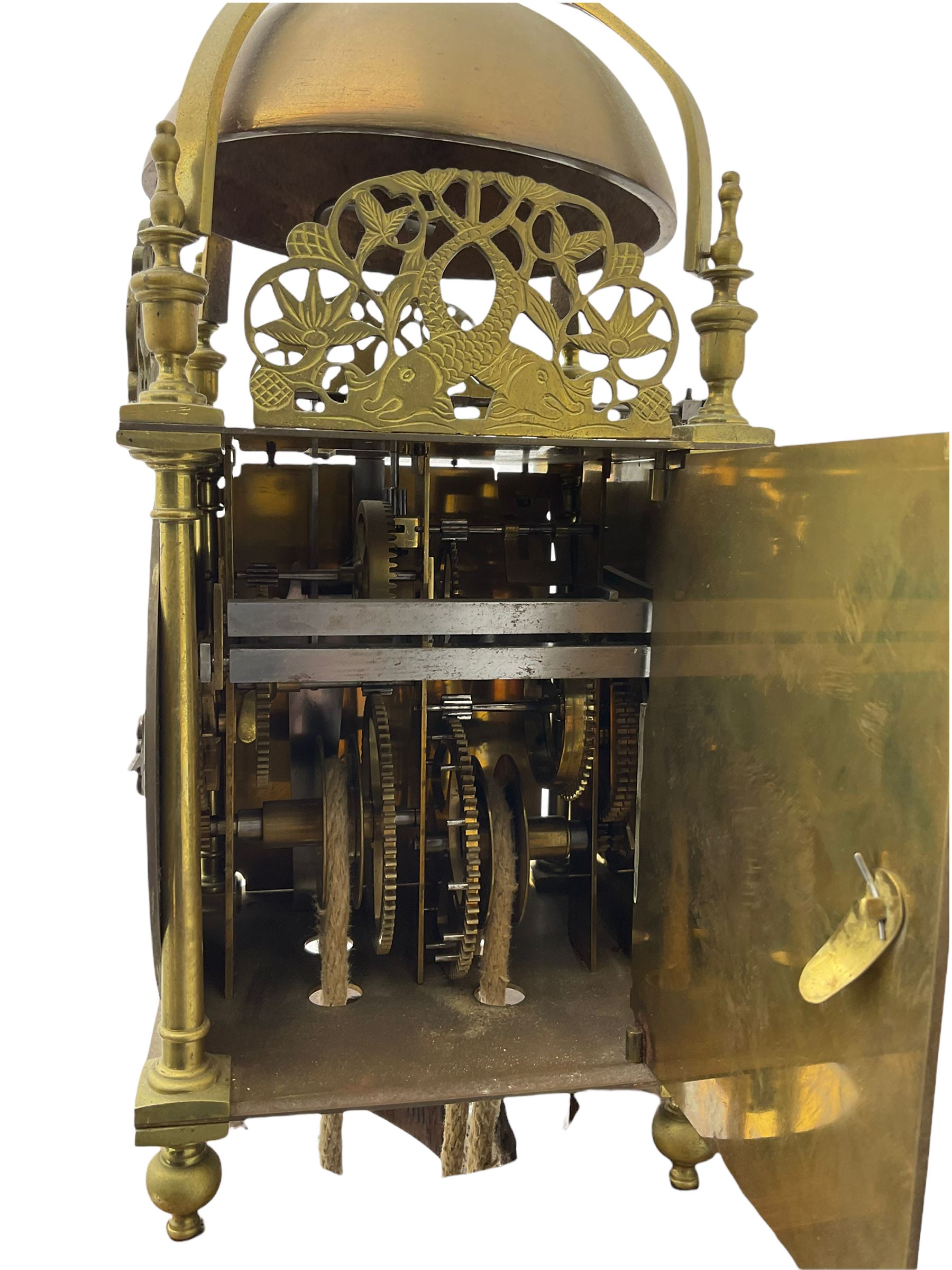 A 20th century replica of a 17th century 30-hour lantern clock with a rope driven verge escapement and countwheel striking, sounding the hours on a bell, with an engraved dial centre, silvered chapter ring and Roman numerals , half hour and quarter hour markers and a pierced and fettled steel hand, with an attached disc engraved “ Clockmaker In Scarborough Ivan Coe, Fecit,”, with engraved side doors, brass finials and dolphin fretwork, on a wooden bracket with pulley.   No weight.
Clocks similar to this were usually individually constructed by engineers working from plans of clocks designed by Claude Reeve, John Wilding, Malcolm Timings and other well-known clockmakers/engineers. 
