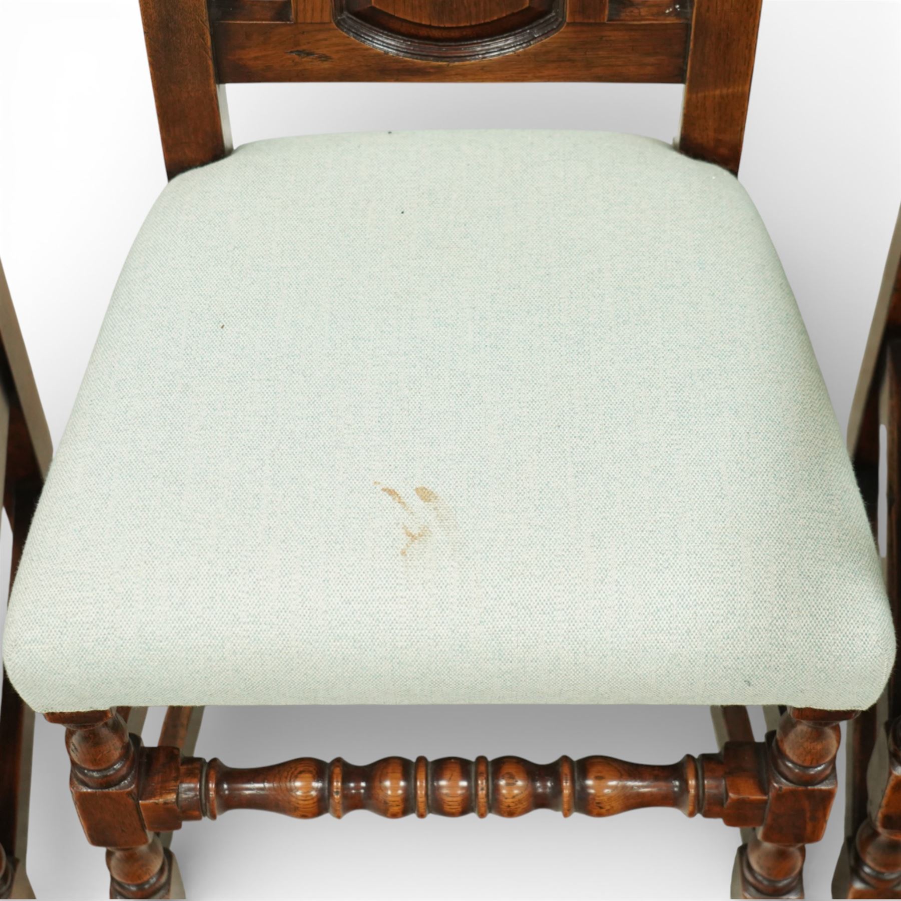 Country House oak high back dining chairs, set of ten comprising eight side chairs and two carvers, each with arched top rail flanked by turned finials over a central fielded panel back, with overstuffed seats upholstered in pale fabric, raised on turned front supports united by stretchers