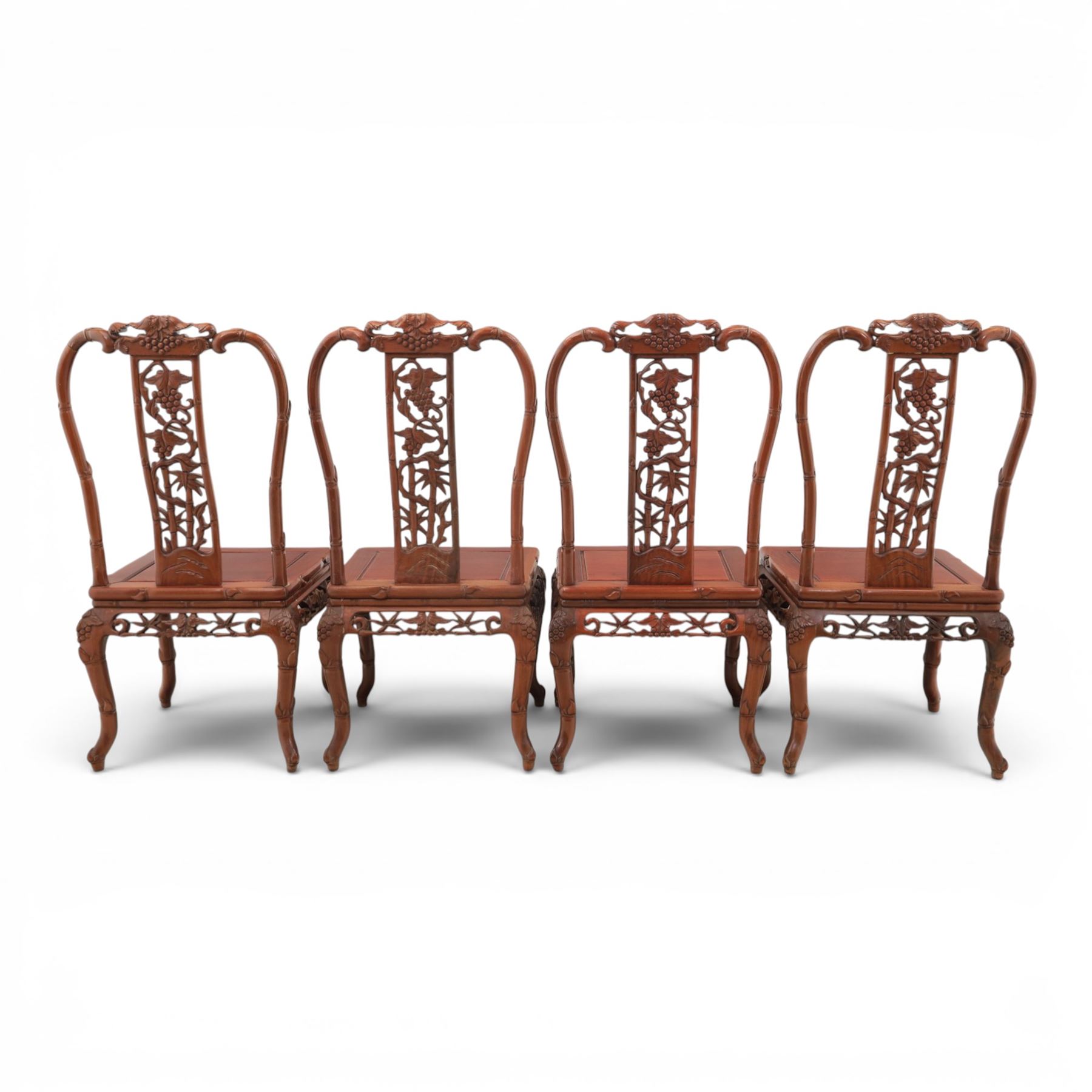 20th century Chinese ornately hardwood dining table and chairs, circular table with 'Lazy Susan' top with pierced carved frieze, raised on a quadriform base with carved foliate detail, the chairs en suite with carved pierced detailing  