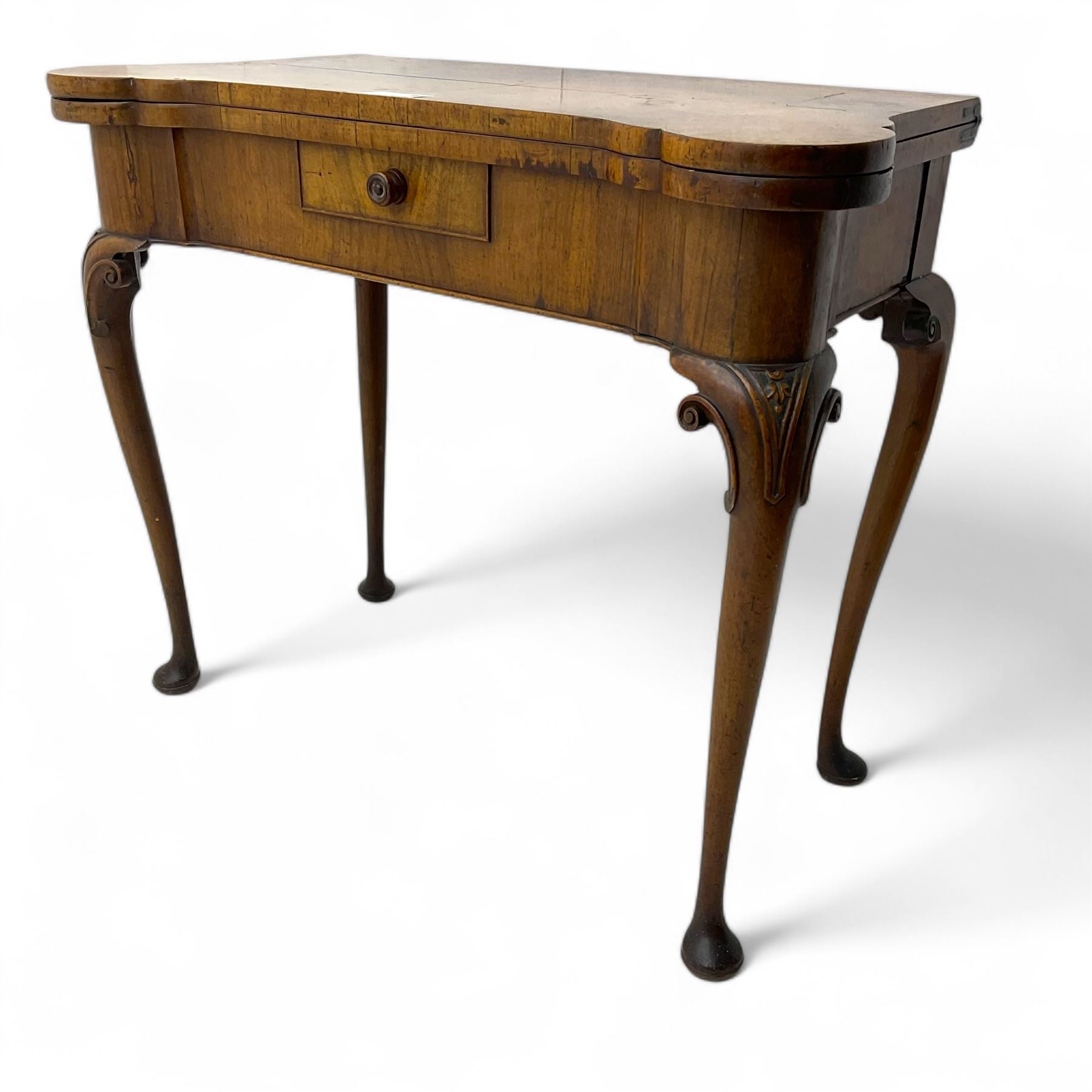 Georgian walnut fold-over card table, shaped rectangular top opening to reveal a baize-lined surface, supported by a concertina pull-out rear mechanism, frieze fitted with single drawer, raised on cabriole supports with foliate carvings terminating in pad feet