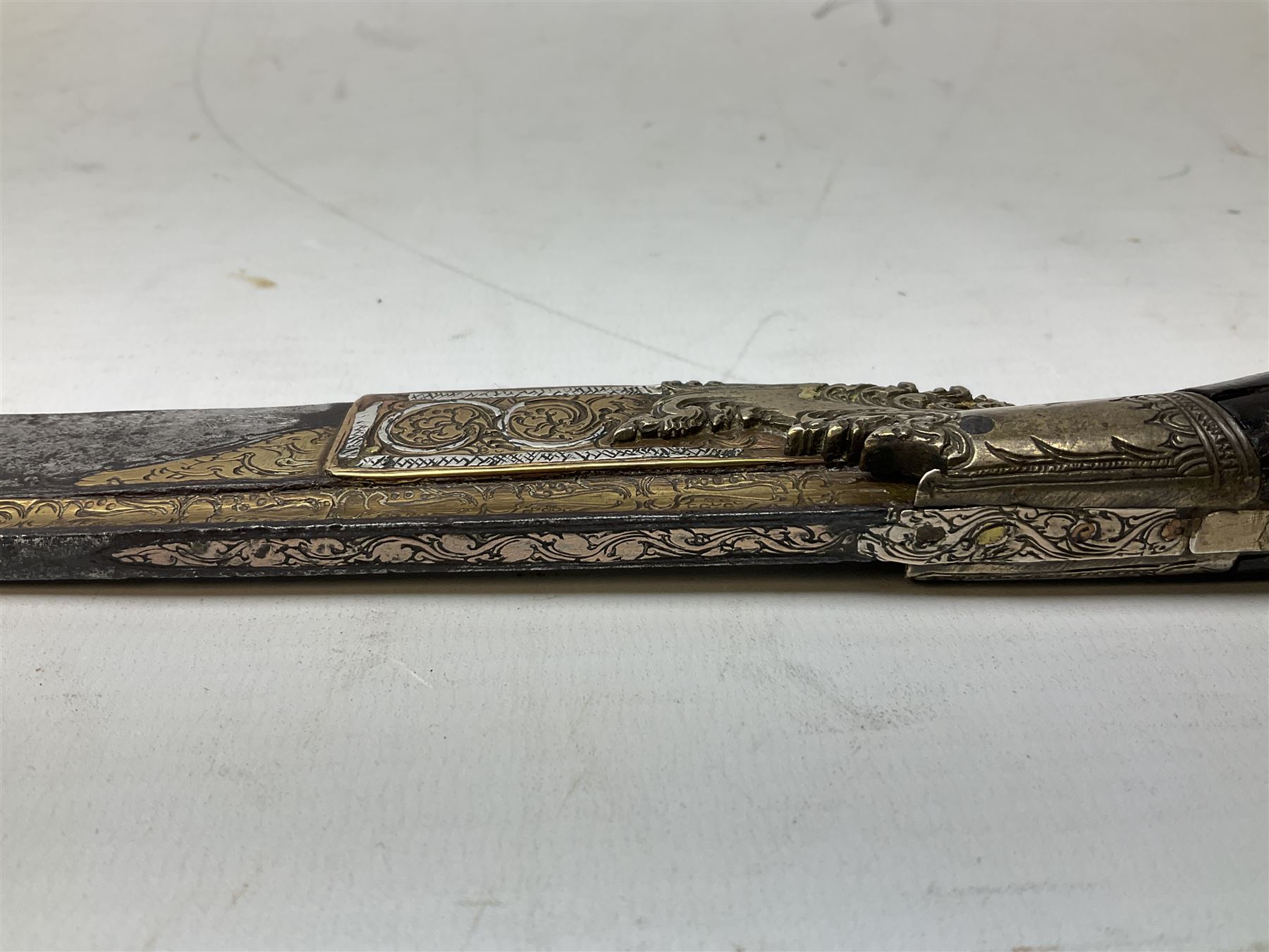 19th century Singhalese knife pia kaetta, the 20cm steel blade inset with yellow and white metal, with metal mounted carved pistol grip, in plain wooden scabbard L33cm overall