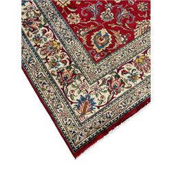 Persian Tabriz crimson ground carpet, decorated with swirling leafy branches and large palmette motifs, the pale ground border decorated with trailing foliate pattern, within floral guard stripes