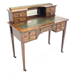 Late Victorian inlaid rosewood writing desk, the raised back fitted with ornate gilt metal gallery, bevelled mirror and four small drawers, rectangular top with leather inset over one long and four short drawers, square tapering supports with brass and ceramic castors