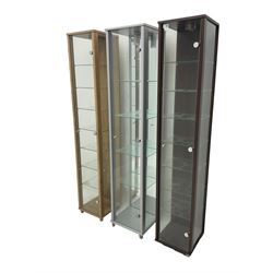 Three narrow glazed display cabinets, single glass door enclosing glazed shelves 