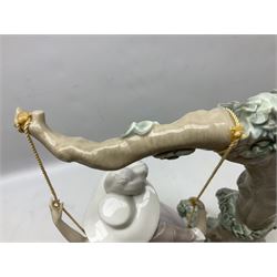 Lladro figure, Swinging, modelled as a woman sat on a swing attached to a tree branch, sculpted by Salvador Debon, no 1297, year issued 1974, year retired 1989, H41cm 