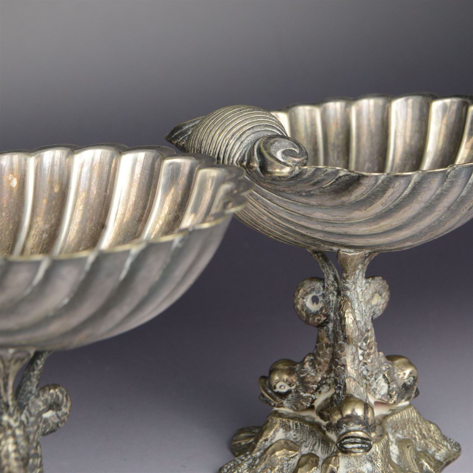 Pair of Victorian silver plated comports, with clam shell bowls supported by three dolphins upon a rocky base, H12cm