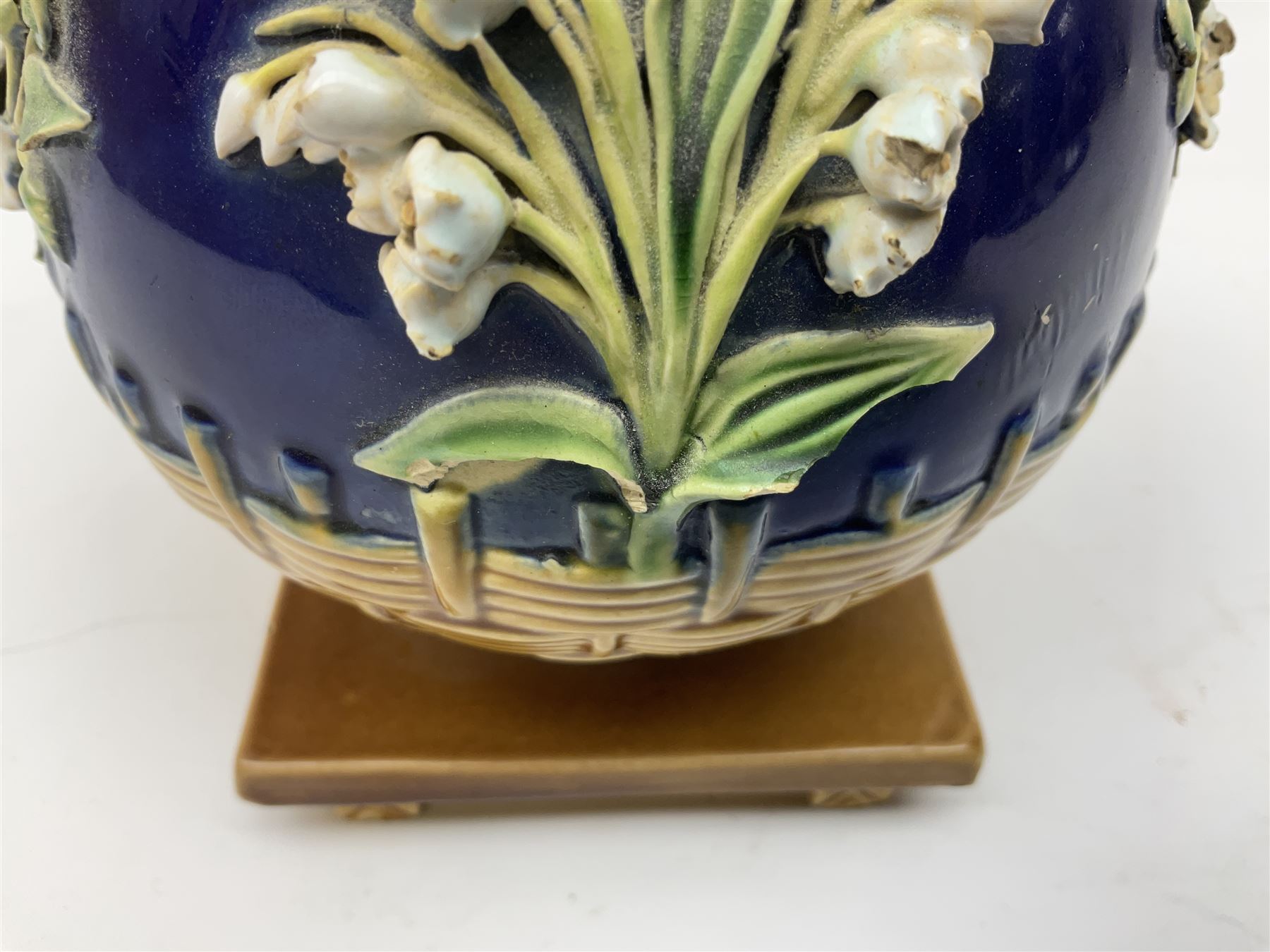 Minton majolica vase, the squat body with twin handles, with part osier moulding and applied Spring flowers against a cobalt blue ground, upon integral square base, impressed beneath Minton 1316, H16.5cm