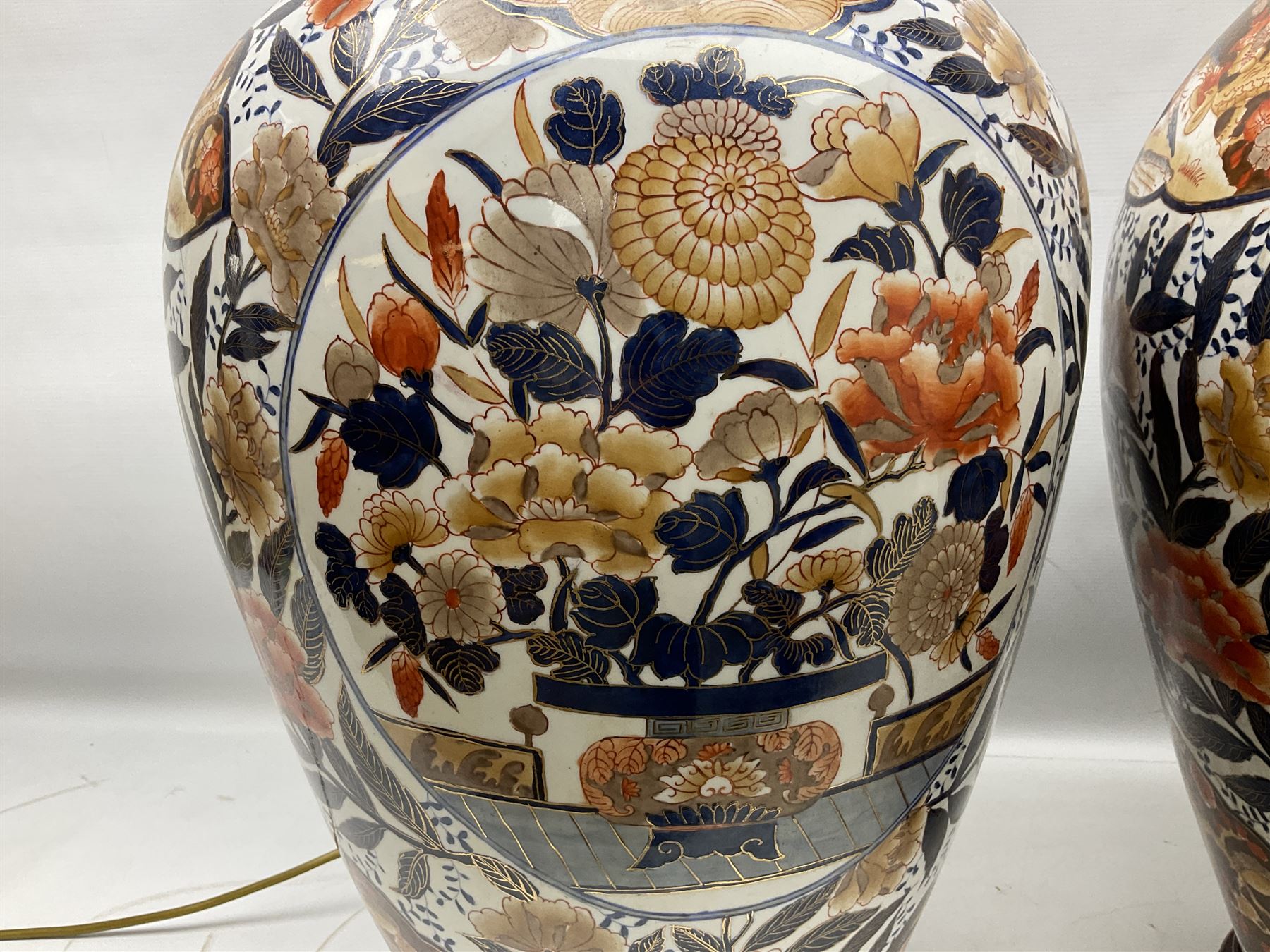 Pair of large and impressive 20th century Japanese Imari table lamps, each of ovoid form, decorated in the Imari palette with roundels containing flowering urns, and shaped panels of birds, set against a white ground decorated with blossoming peonies, lamp base (not including fixtures) H56.5cm overall including shade H89cm