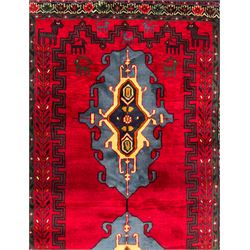 Northwestern Persian Cirjan hand-knotted carpet, madder red field with three linked stepped lozenge medallions in blue, ivory and green, flanked by angular motifs within a dark green border of serrated leaves and rosettes 