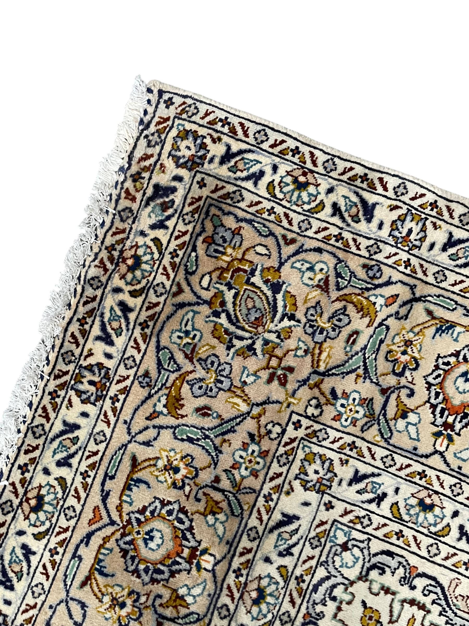 Persian Kashan ivory ground carpet, central pole medallion surrounded by swirling leafy branches and stylised plant motifs, scrolled foliate spandrels, the main border decorated with scrolling pattern and repeating palmettes, within floral patter guard stripes 