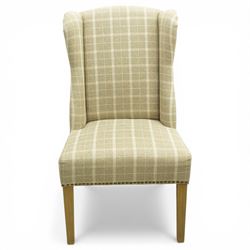 Contemporary wing back dining chair, fully upholstered in beige plaid fabric with studded edge detail, shaped back and seat, raised on tapering supports