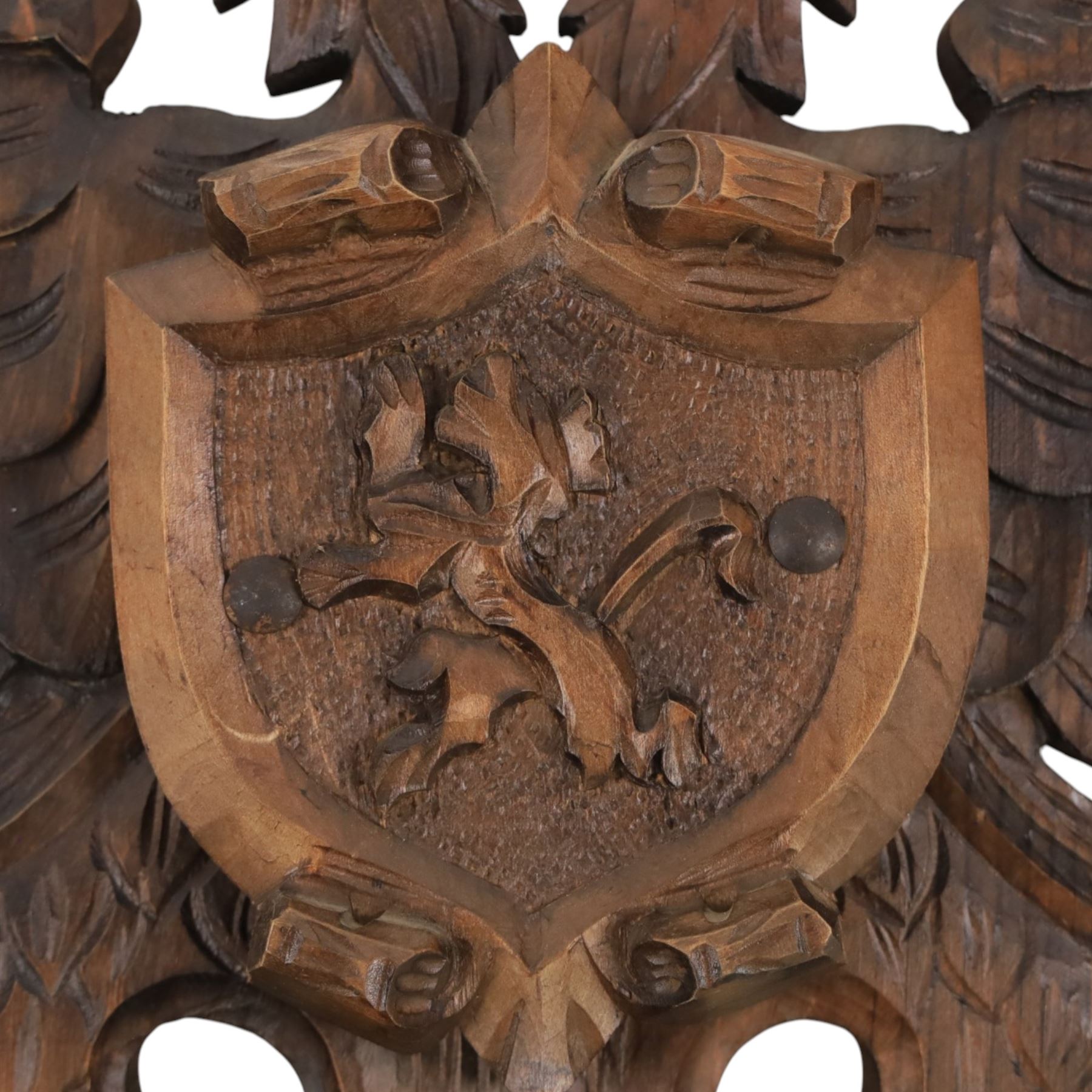 Carved wooden wall plaque, decorated with foliate scrolls, with two reproduction swords attached, together with five other wooden plaques with foliate scrolls and shields