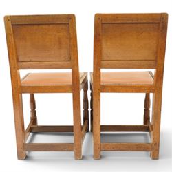Mouseman - pair of 1940's adzed and panelled oak chairs, the rectangular adzed back-panel over seats upholstered in orange-tan leather with studwork, raised on turned octagonal supports united by box stretcher, with carved mouse signature, by the workshop of Robert Thompson of Kilburn
Provenance: purchased directly from the Kilburn workshop in the late 1940s