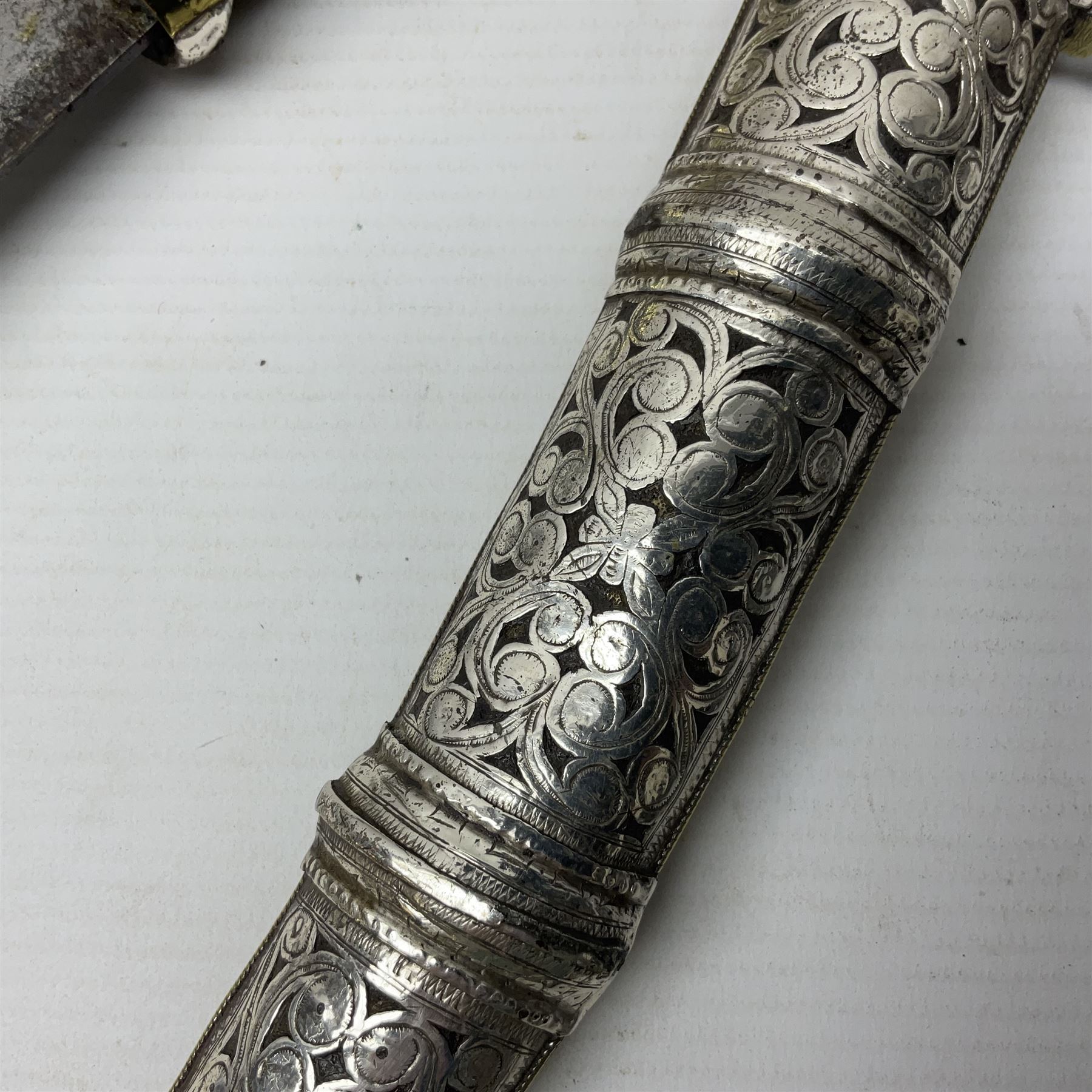 Moroccan jambiya dagger with 24.5cm plain curved blade stamped LONDON to the ricasso area, the hilt and scabbard overlaid with plain sheet brass to the back and ornate silver coloured metal to the front; waisted grip and arched pommel; two pyramid mounts to the scabbard L41cm overall; large billhook with curving blade and stacked leather washer grip; and a reproduction halberd blade (3)