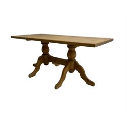 Rectangular waxed pine dining table, on turned pedestals joined by stretched with splayed supports