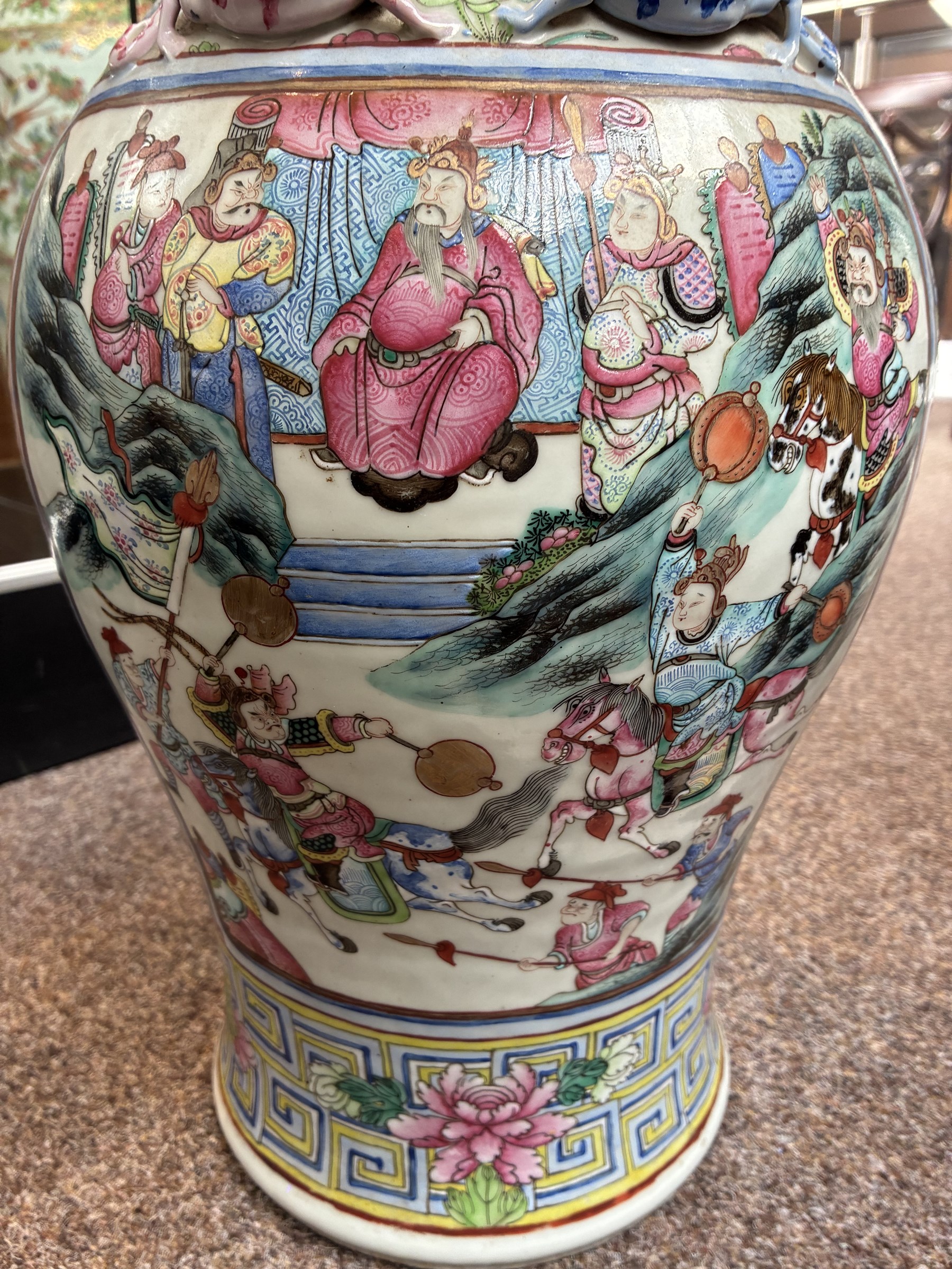 Large pair of 19th century Cantonese famille rose vases, each painted with various courtly scenes, including a display of warriors fighting on horseback before an official and his attendants, double Buddhist lion handles and applied at the shoulders with chilong, the lower band painted with Greek key motif, H58cm (2)