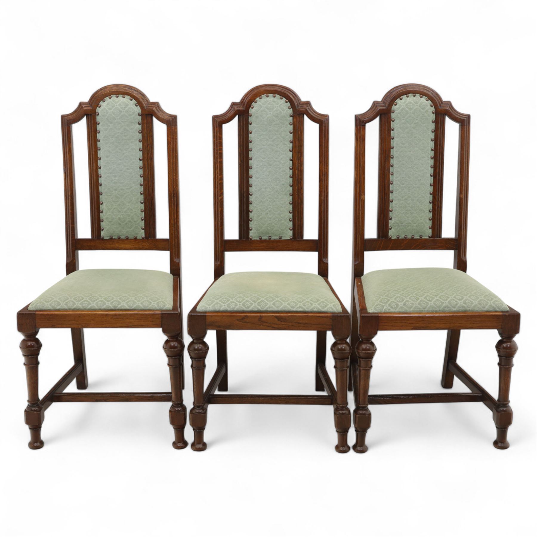 Victorian mahogany extending dining table, rectangular top with chamfered corners above a plain frieze raised on turned reeded legs with castors and two additional leaves, 197cm fully extended, and a set of six early 20th century oak upholstered chairs with drop-in seats, arched panelled back splat and close studded border on turned front legs joined by stretchers, 47x41x109cm 