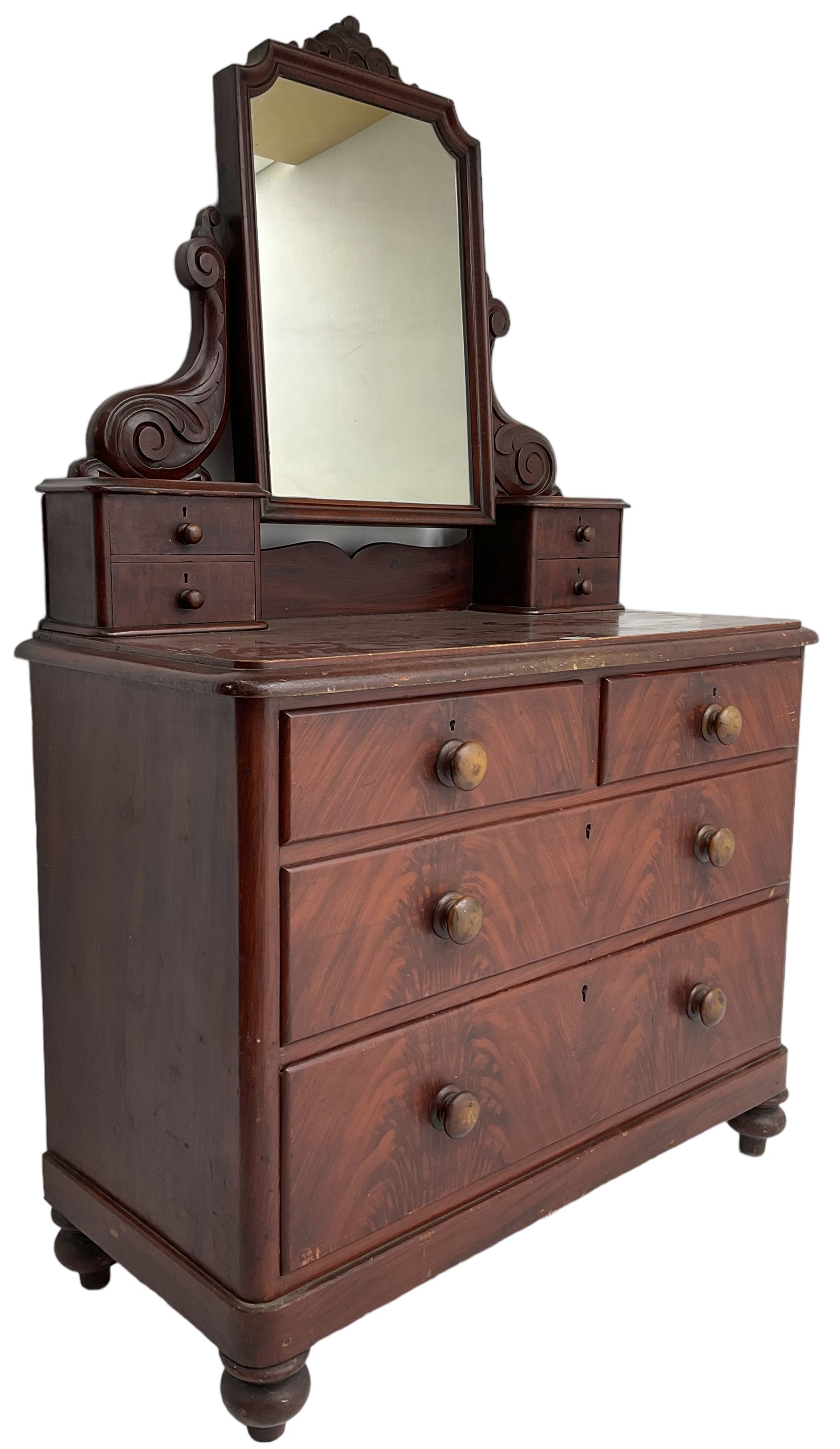Victorian scumbled pine dressing chest, raised swing mirror in moulded frame with scrolled carved pediment, foliage S-scroll carved supports over trinket drawers, moulded rectangular top with rounded corners over two short and two long drawers, skirted base on turned feet, scumbled to resemble mahogany 