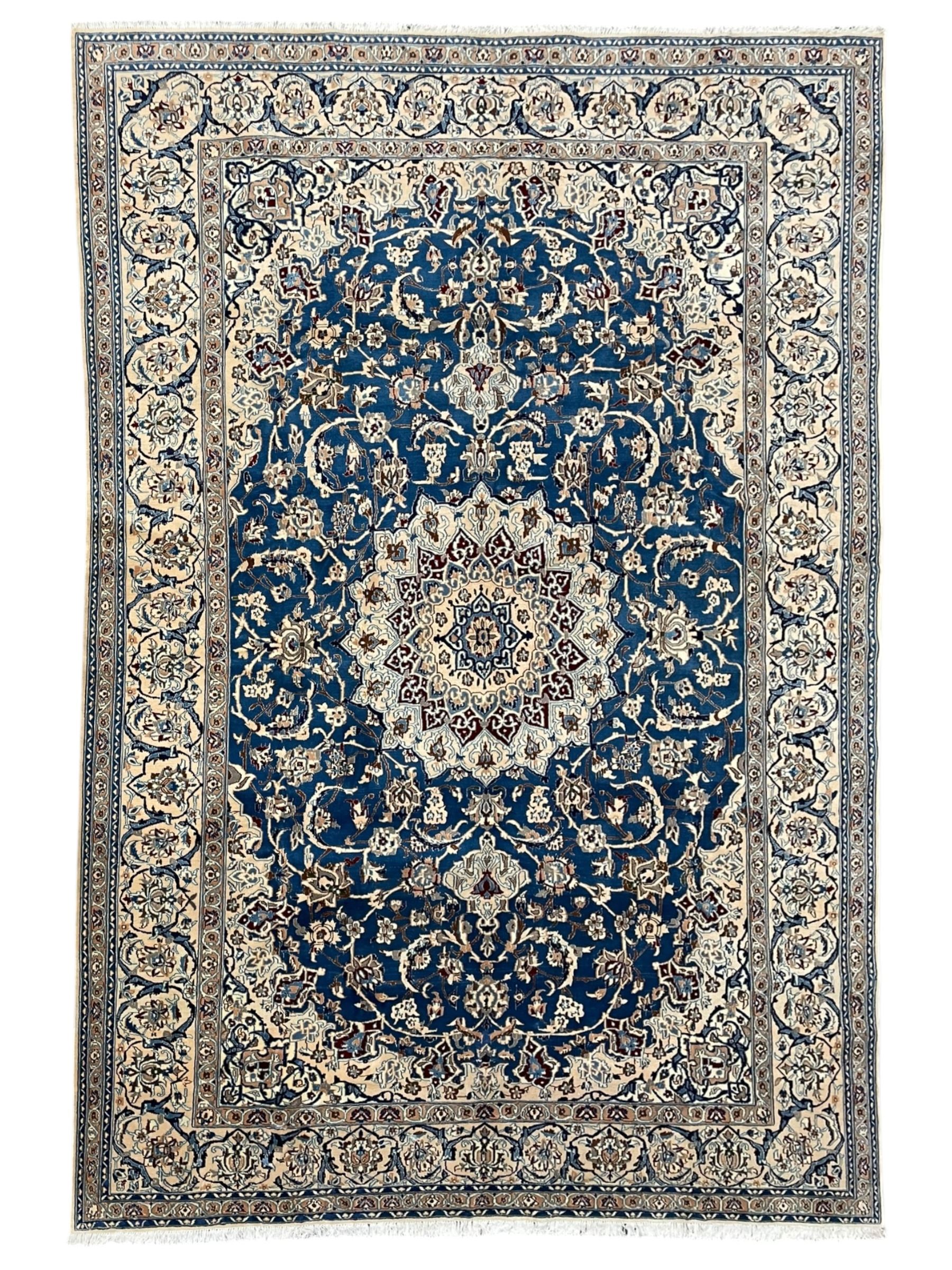 Persian Kashan blue ground rug, central floral rosette medallion within a field of swirling branches and palmettes, the border with trailing pattern interspersed with stylised plant motifs