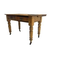 Traditional rustic pine dining table, rectangular top fitted with two drawers, raised on turned tapering supports on ceramic castors