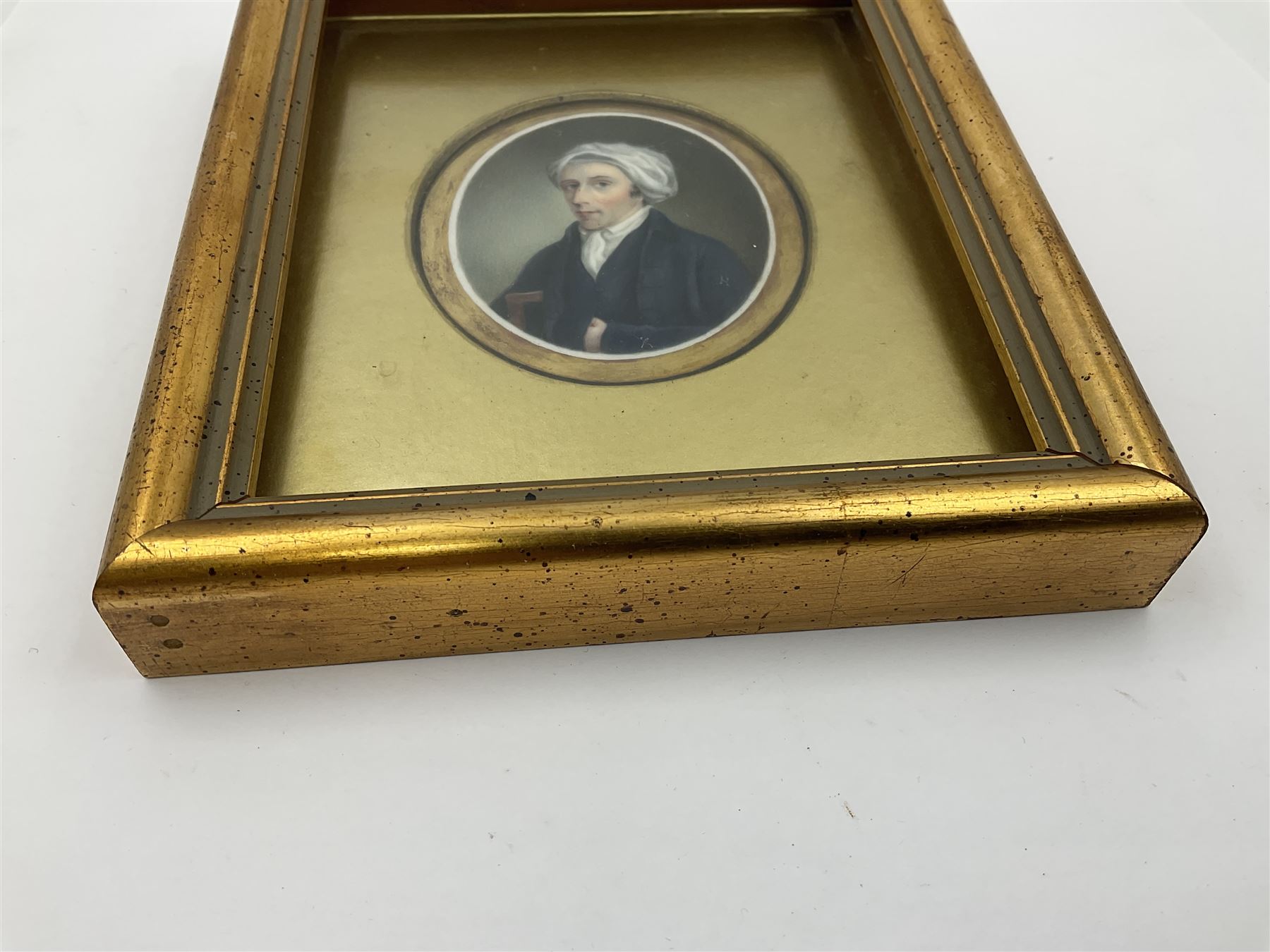 English School (18th century)
Portrait miniature upon ceramic plaque 
Head and shoulder portrait of a gentleman in blue coat and white turban, holding book under one arm
Indistinct inscription verso
Within gilt mount and gilt frame under glass
Portrait 7cm x 5.5cm 
Plaque 14cm x 11.5cm
Frame 16cm x 13.5cm
