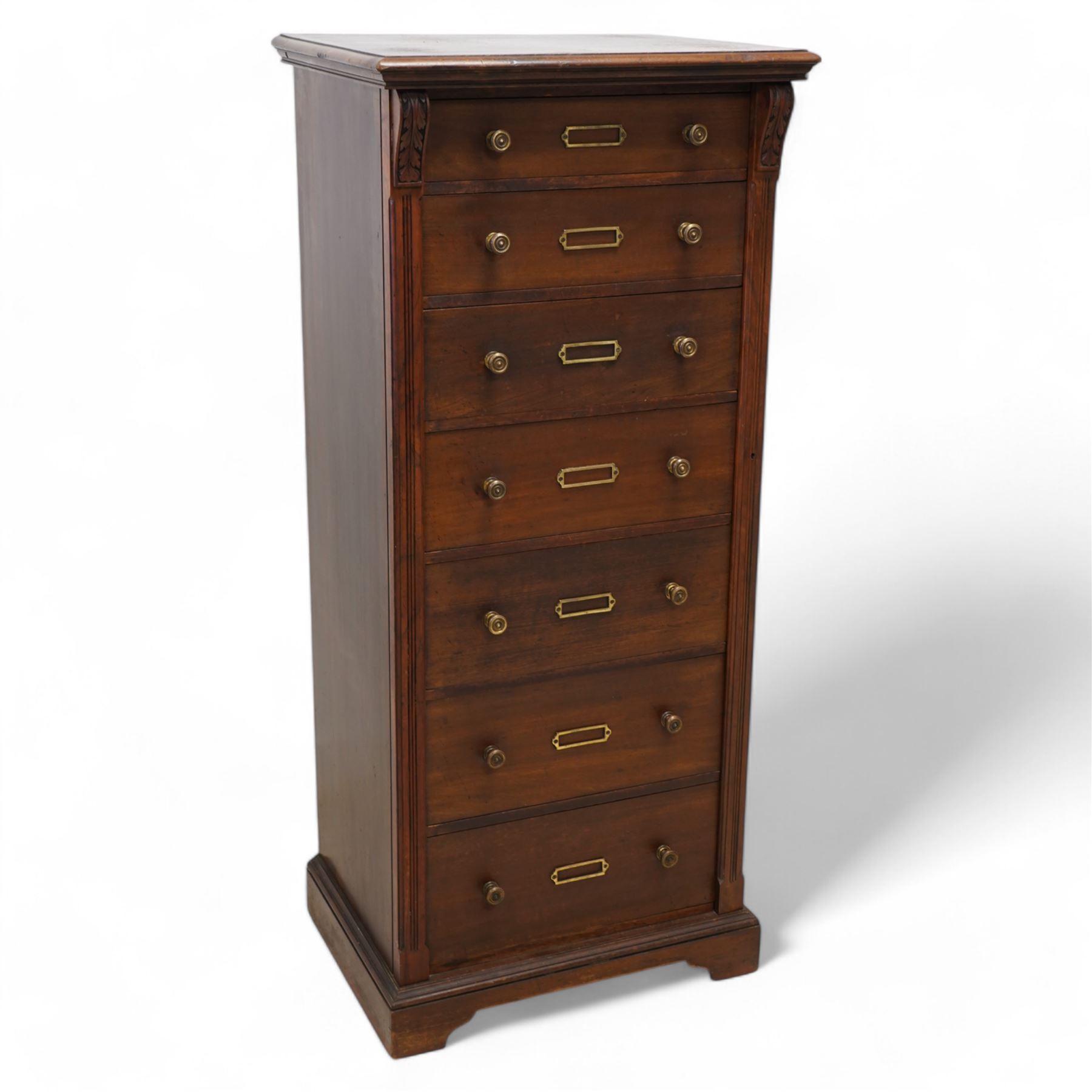 Thomas Edwards & Sons (Newcastle 1877-1882) - Victorian walnut Wellington chest, rectangular moulded top over seven graduating drawers, each fitted with brass handles and label holders, flanked by foliate carved brackets over reed-moulded and chamfered uprights, on shaped skirted base
