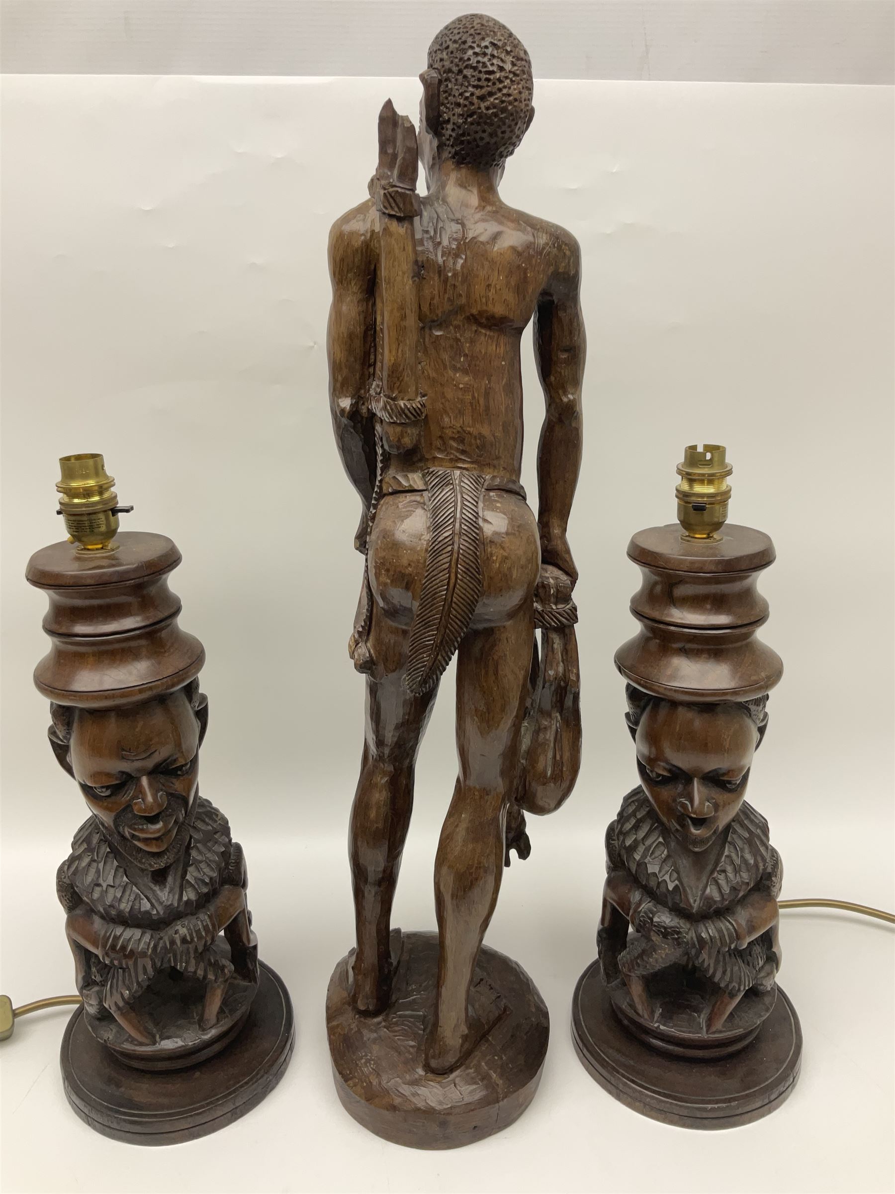 Pair of 20th century carved wood table lamp with African busts and figures, together with a carved wooden figure and soapstone figure, lamps H44cm