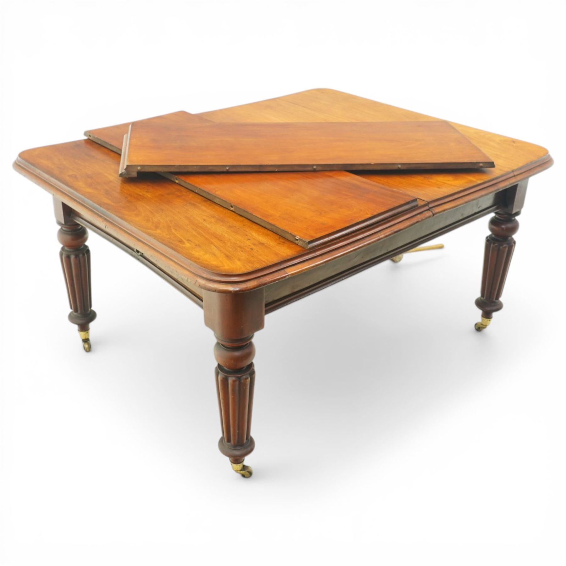 Victorian mahogany extending dining table, rounded rectangular top with moulded edge and two additional leaves, on four turned and fluted supports with brass caps and castors, extension mechanism beneath, in need of restoration