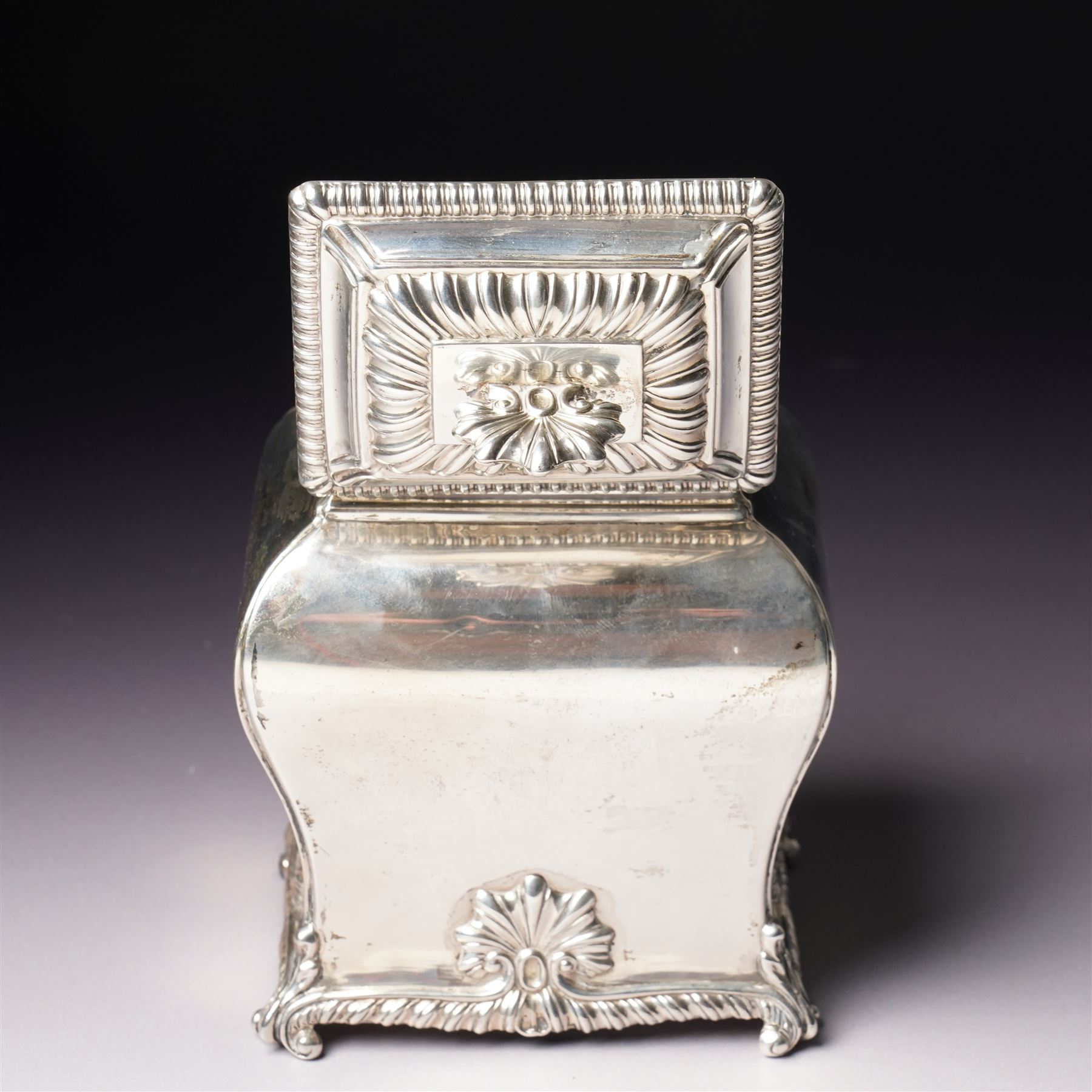 Edwardian silver tea caddy of bombe outline with shell moulded finial, shell moulded and gadrooned base on scroll feet H15cm London 1902 Maker Thomas Bradbury & Sons