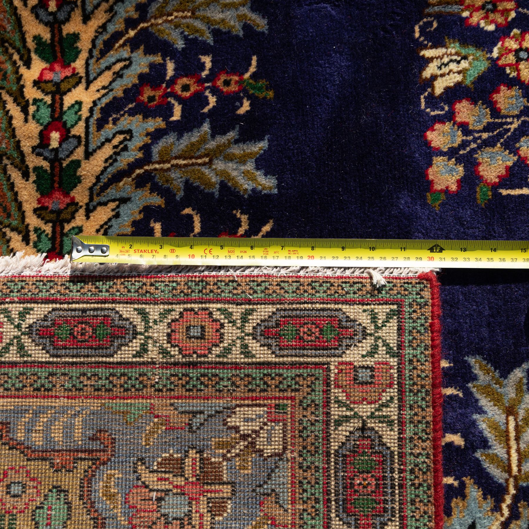 Persian Kashan rug, deep blue ground with central red and ivory lobed medallion framed by dense floral motifs, multiple borders with foliate and geometric design in red, blue and ivory, from the central Iran region