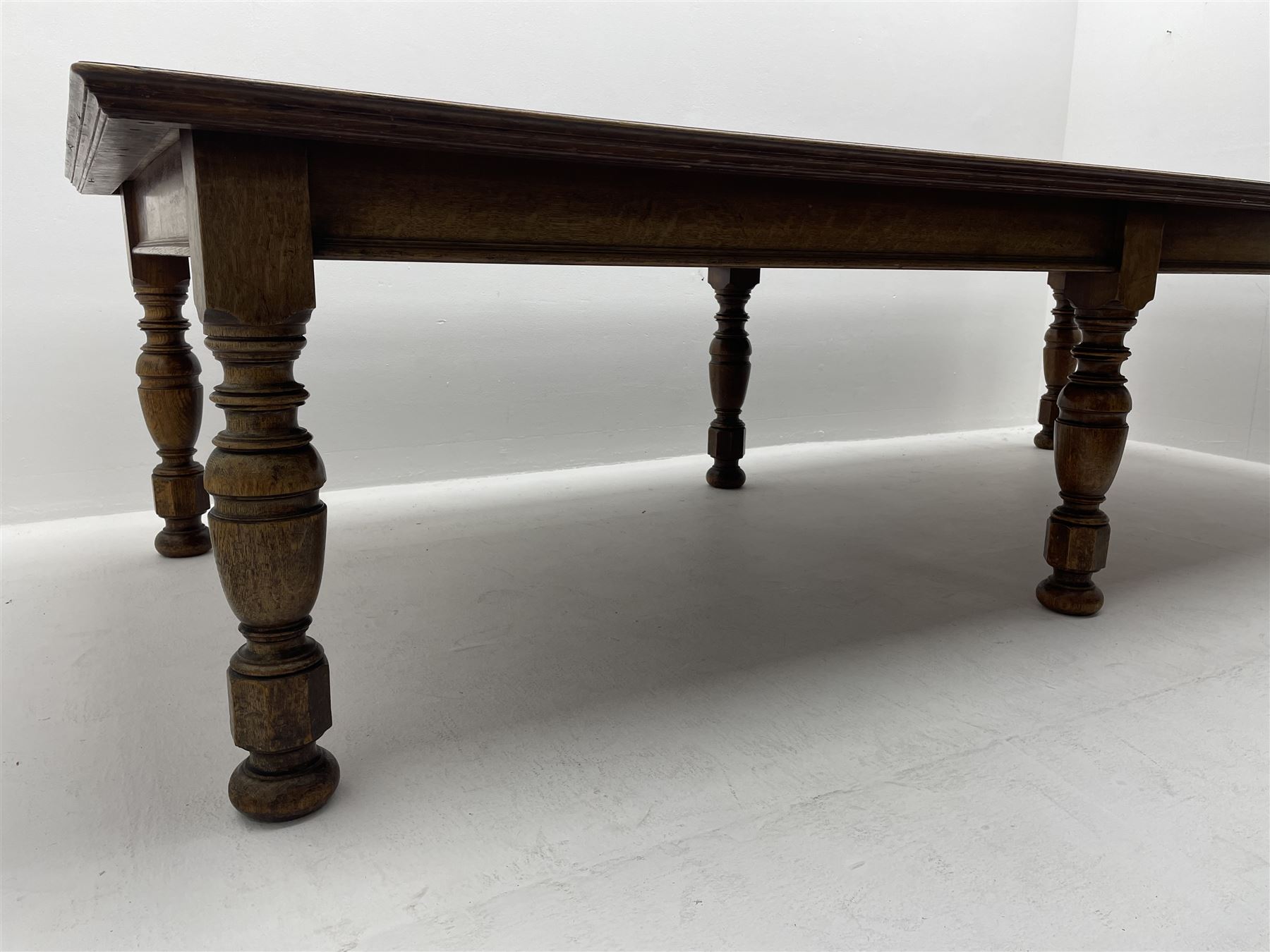 Large early 20th century oak boardroom table, rectangular moulded top on six turned and faceted supports 