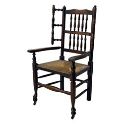 Early 19th century ash armchair, the back with winged spindles extending from a shaped top rail, above a splat of two rows of vertical spindles, with curved arms and a rush seat, raised on turned supports united by double stretchers terminating in castors