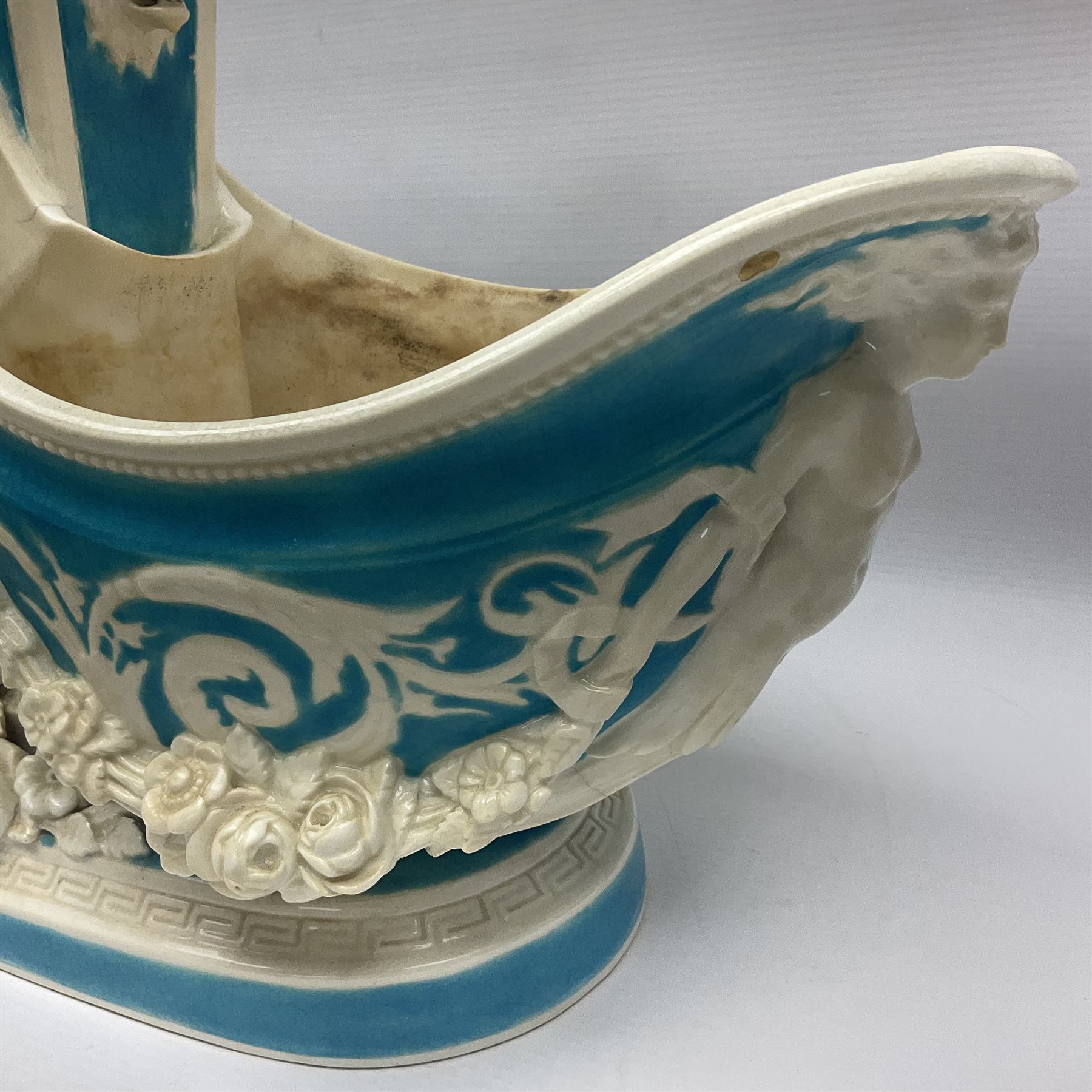 Rare 19th century Minton turquoise glaze majolica 'The Reader' flower holder, after Albert Carrier-Belleuse, modeled as a maiden in classical drapery reading whilst leaning against the pillar back of the helmet shaped cistern detailed with a caryatid and floral swags, the whole upon an oval plinth with Greek key border, with impressed marks beneath, H44cm