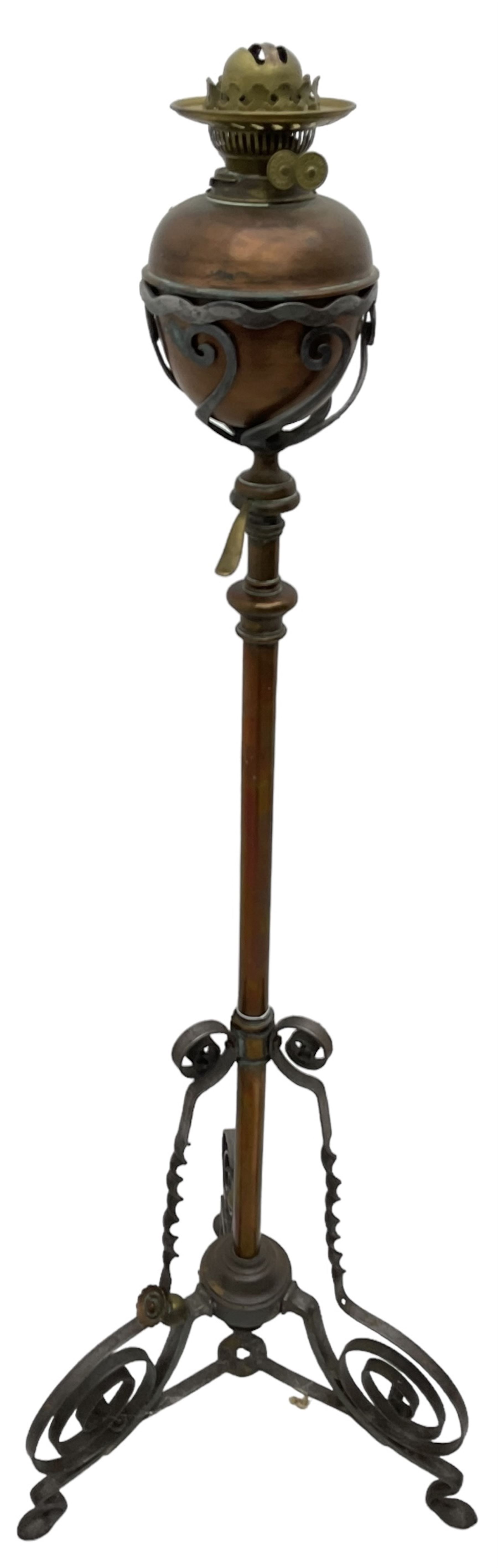 Late 19th to early 20th century wrought metal and copper telescopic oil standard lamp, the lamp and reservoir on scrolled supports with waved band, handle operating telescopic action, tripod base with scrolled terminals and twisted decoration, splayed pad feet 