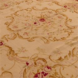 20th-century Aubusson-style tapestry wall hanging of square form, woven with a central floral medallion composed of delicate sprays in soft pinks, creams, and muted greens, framed by scrolling acanthus ornamentation and floral cartouches to each corner, all set within a pale ivory ground and enclosed by a terracotta toned border 