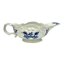 Large 18th century Lowestoft sauce boat, circa 1770, the body decorated with Hughes type floral moulding, and painted in underglaze blue with an Oriental landscape, and foliate sprigs, L23cm