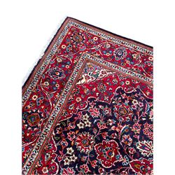 Persian indigo ground rug, the central crimson pole lozenge medallion surrounded by interlacing floral patterns, the main border with repeating plant motifs connected by scrolling branches