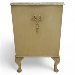French design cream painted three drawer commode, shaped front with floral garland appliqués, fluted uprights and acanthus carved cabriole legs terminating in scroll feet