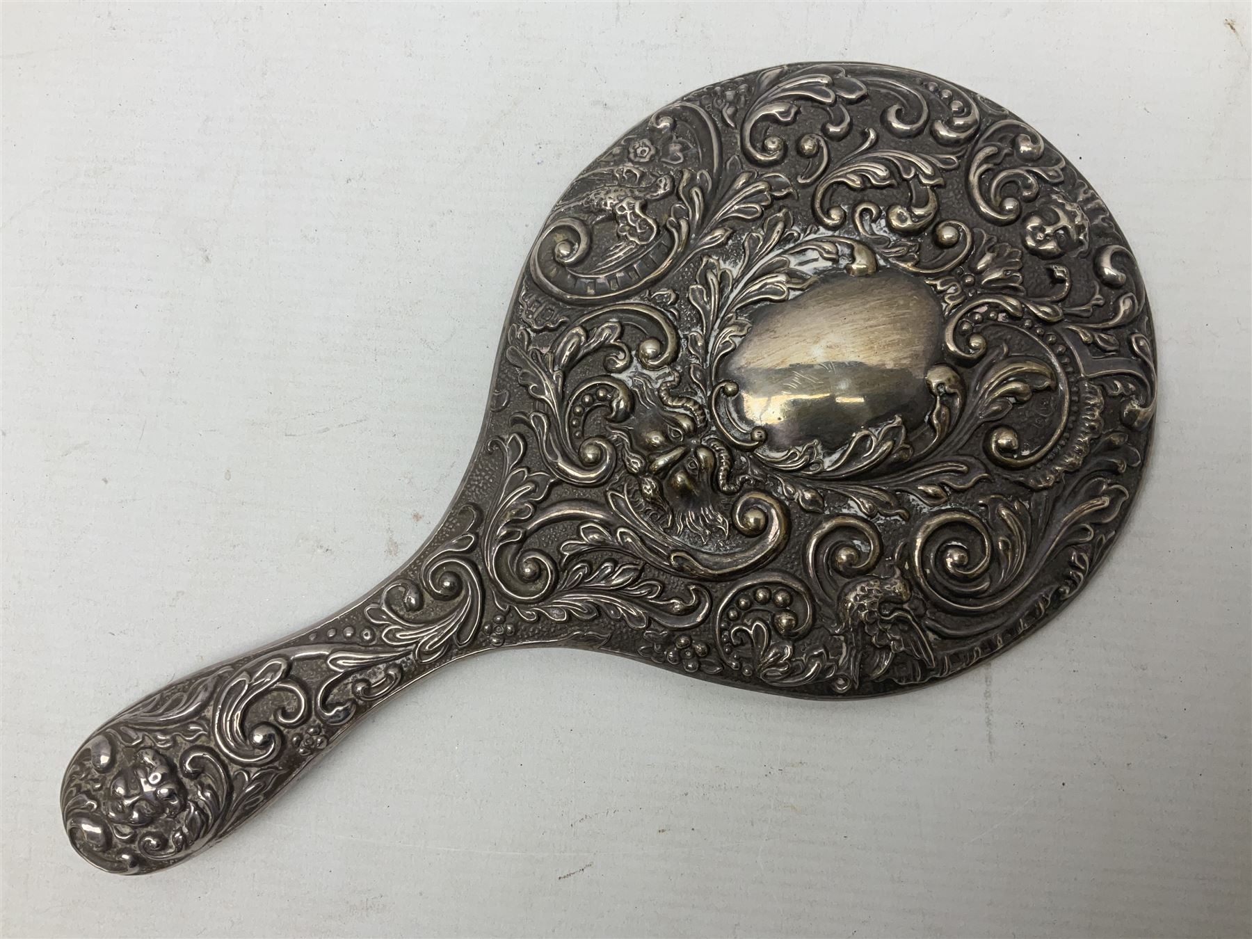 Silver mounted dressing table mirror, embossed with birds, masks, and foliate and C scrolls, hallmarked Birmingham, and fruit knife with mother of pearl handle and silver blade, (2)