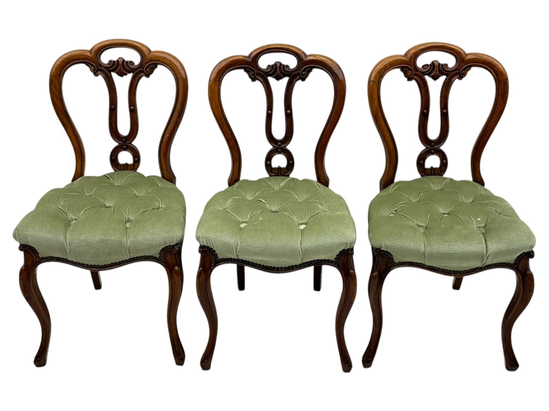 Set of six carved Victorian walnut balloon back dining chairs, button upholstered in green velvet fabric, back with foliate carved decoration supported on scroll form legs 