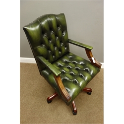  Reproduction beech framed office swivel desk chair upholstered in deeply buttoned green leather, on five splayed supports, W62cm  