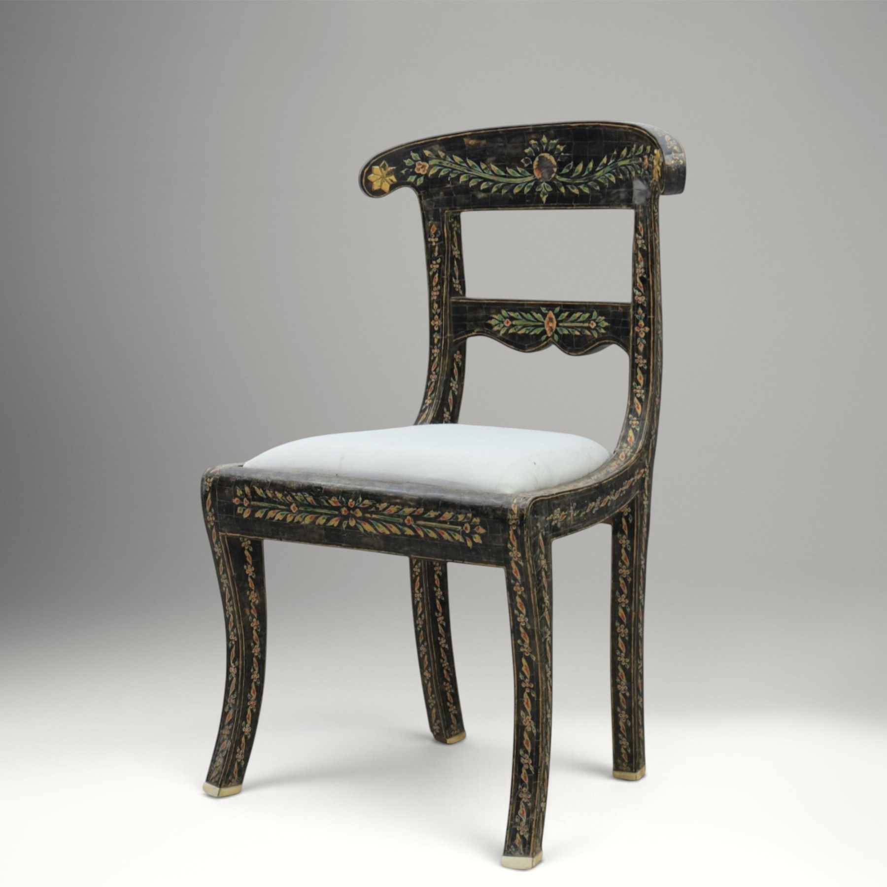 Early 20th century Anglo-Indian painted and inlaid armchairs, each with shaped top rail decorated with polychrome floral motifs above turned spindle galleries, shaped open arms and upholstered seats, on square supports with similar painted decoration