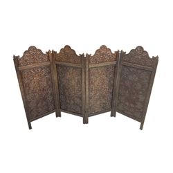 Burmese carved hardwood folding screen, four shaped arch panels profusely carved with foliage 