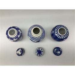 Six Chinese ginger jars, predominantly of blue and white design decorated with blossoming branches, all with lids, housed on various hardwood carved stands, some with character marks beneath