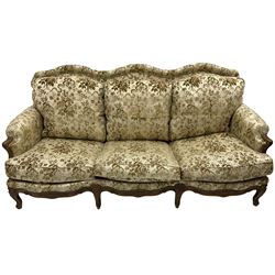 Early 20th century French carved stained beech framed three piece suite, comprising two deep seated armchairs (W76cm D93cm H87cm) and serpentine back three seat sofa (W195cm H87cm), upholstered in ivory ground floral patterned fabric with studwork, raised on foliate carved cabriole supports